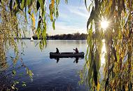 451_1311  Ein Kanu und ein Segelboot auf der herbstlichen Aussenalster - die tiefstehende Sonne strahlt durch die herblich gefrbten Bltter einer Weide, die am Ufer des Hamburger Sees steht.