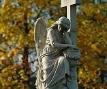 16_038161 trauernder Friedhofsengel vor gelben Herbstlaub - der Engel kniet vor einem Kreuz und hat den Kopf in die Hand gesttzt.  www.christoph-bellin.de