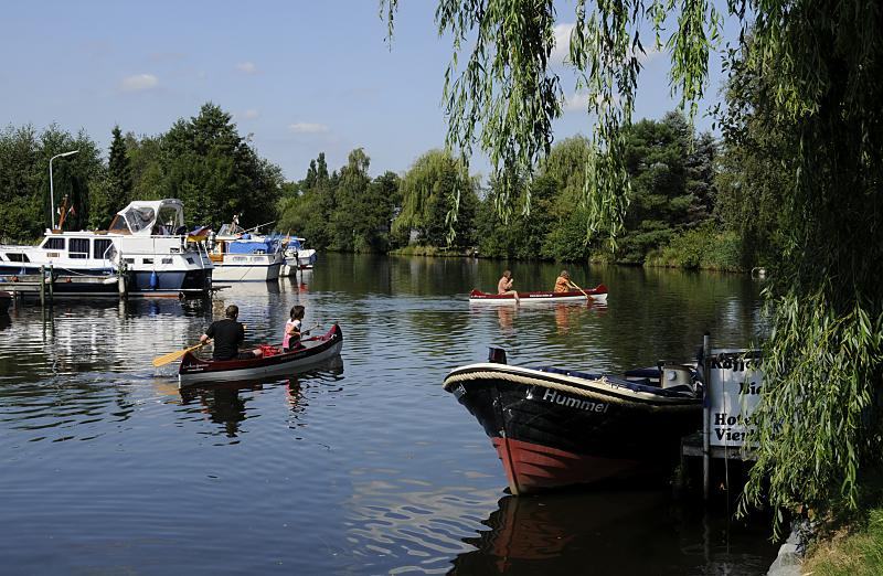 011_26065 Zwei Kanus fahren auf der Dove-Elbe in der Nhe von "Auf der Bge"; grosse Motorboote liegen am Ufer des Flusses am Steg, das Tuckerboot HUMMEL hat am Anleger des Hotels Vierlandentor am Curslacker Deich fest gemacht.    www.christoph-bellin.de