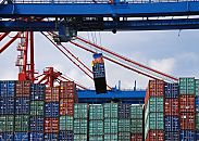 011_15614 die Ladung des Containerschiffs wird entladen; ein Container schwebt an der Containerbrcke und wird an Land gebracht. In der kleinen Kanzel unter der Brcke sitzt der Fhrer der Krananlage und steuert von dort aus seine Arbeit im Hamburger Hafen.