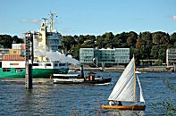 011_22976/00 ein Containerschiff fhrt auf der Elbe in Hhe Hamburg Neumhlen Richtung Nordsee; der historische Schlepper dampft Richtung Hafen - ein Segelboot segelt am Elbufer - an der anderen Elbseite die neue Architektur Hamburgs im ehem. Hafengebiet Altonas.