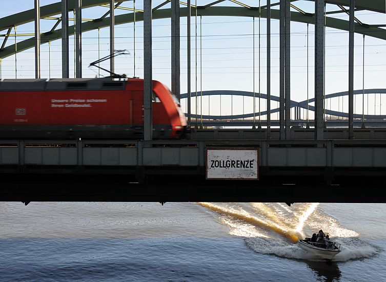 017_19018 ein roter Triebwagen auf den Elbbrücken beim Schild Zollgrenze . auf der Elbe fährt ein Sportboot / Motorboot in voller Fahrt.   ©www.christoph-bellin.de