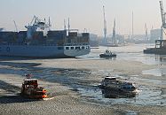 001_22730 Die Elbe ist mit Treibeis bedeckt; ein Containerschiff wird von einem Schlepper rckwrts in das Hafenbecken vom Tollerort Terminal geschleppt. Eine Hafenfhre bahnt sich ihren Weg durch das Eis auf der Elbe und steuert den Anleger "Dockland" an, whrend ein weiteres Fahrgastschiff mit Touristen an Bord auf seiner Hafenrundfahrt ist.