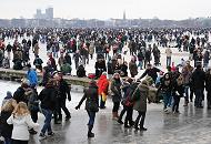 2048 Die Menschen strmen auf die zugefrorene Auenalster - andere sitzen auf einem Holzsteg, ziehen ihre Schlittschuhe an oder beobachten das bunte Treiben. 