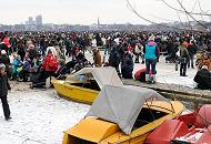 2058 Dicht an dicht gehen die Menschen auf der zugefrorenen Alster; Kinder spielen auf dem Eis. Am Holzsteg liegen einige Boote einer Bootsvermietung - die kleinen Schiffe sind im dicken Eis festgefroren. 