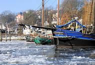 3065 Die historischen Schiffskutter liegen vertut im Museumshafen Oevelgnne - Eis bedeckt das Hafenbecken; die Schiffe sind eingefroren. Hinter den Masten der Kutter die Wohnhuser am Elbstrand von Hamburg Oevelgnne. 
