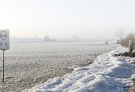 3146 Ein Frachtschiff fhrt Hhe Finkenwerder durch das dichte Eis elbabwrts - das Elbufer ist mit einer Eisschicht bedeckt; Fussgnger gehen auf dem schmalen Uferstreifen und geniessen das schne Winterwetter in Hamburg.