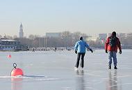 42_5592 Ein Paar nutzt den sonnigen Wintertag und luft Schlittschuh auf der Aussenalster - die Bojen vor einer Segelschule sind im dicken Eis festgefroren. Hamburg im Winter - Eislaufen auf der zugefrorenen Aussenalster. 
