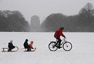 64_5069 Der Hamburger Stadtpark ist eingeschneit. Ein Vater zieht mit seinem Fahrrad die zwei Schlitten seiner Kinder durch den Schnee ber die groe Wiese. Bilder vom Winter in der Hansestadt Hamburg - Winterfreuden im Hamburger Stadtpark.