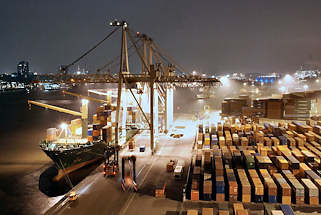011_15288 ein Containerschiff liegt am Kai des Container Terminals Burchard, auf der anderen Seite der Elbe die beleuchteten Huser von Hamburg Neumhlen. Containercarrier transportieren die Container auf die Lagerflche, auf der die Metallboxen in dichten Reihen  gestapelt sind. Der Hamburger Hafen liegt mit z. Zt. 8.1 Mio TEU weltweit auf Platz acht der Containerhfen. TEU = Container, die 20 Fu Lnge (6,096 m) + die Breite von 8 Fu ( 2,44 m) haben; (Twenty-foot Equivalent Unit)