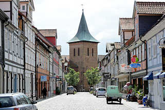 7385 Blick durch die Kirchstrasse in Lüchow zum Kirchturm der St. Johanneskirche. Fachwerkhäuser mit Wohnungen und Geschäften.
